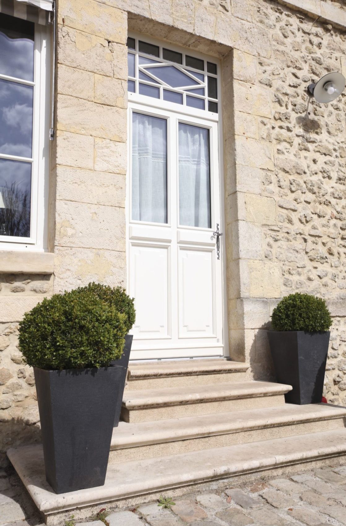 une porte blanche d'extérieure accompagnée de pots de fleurs