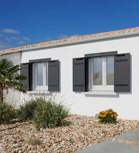 un pan de mur avec ses fenêtres dont les volets sont ouverts et noirs